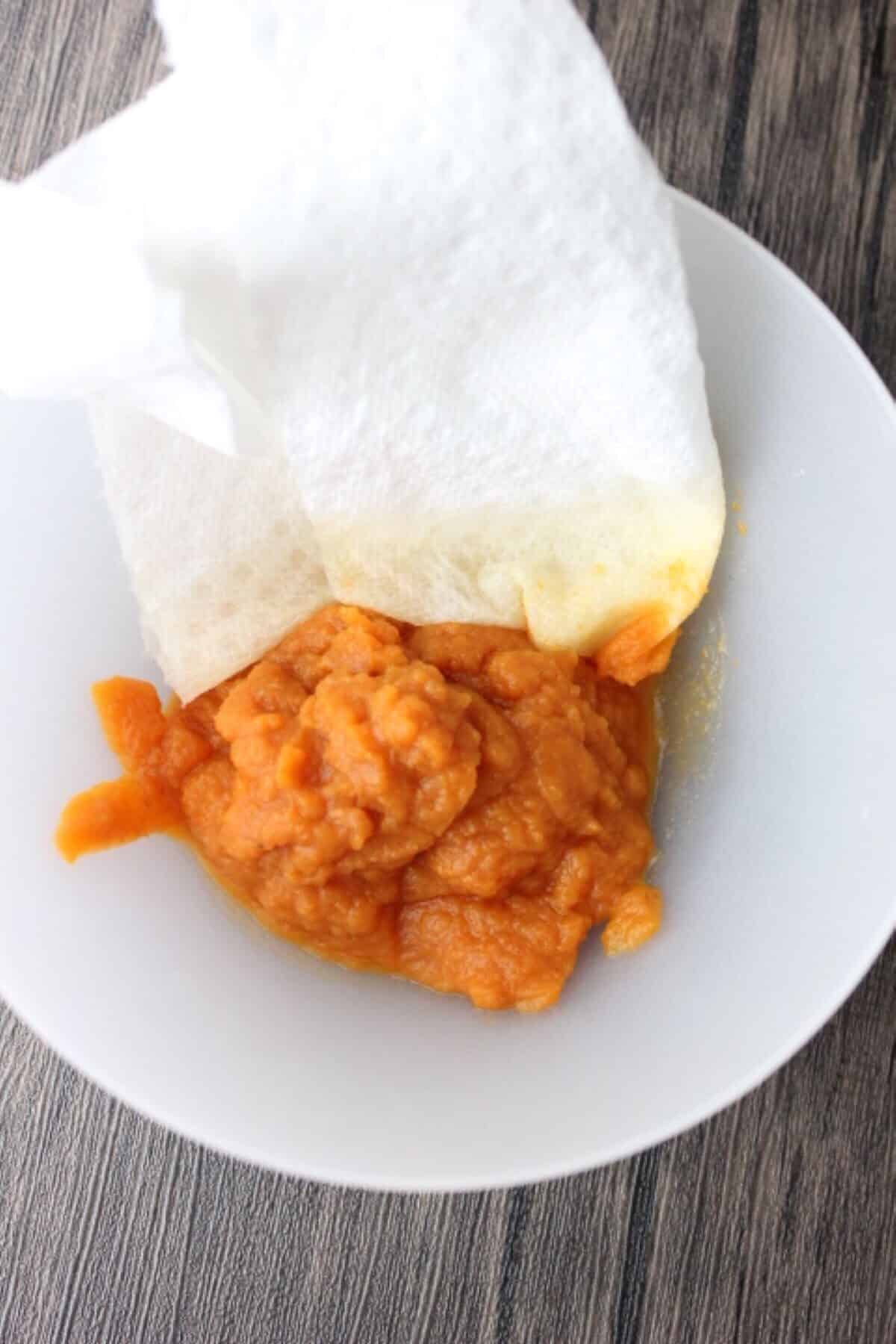 Image of pumpkin puree in bowl with paper towel for blotting.