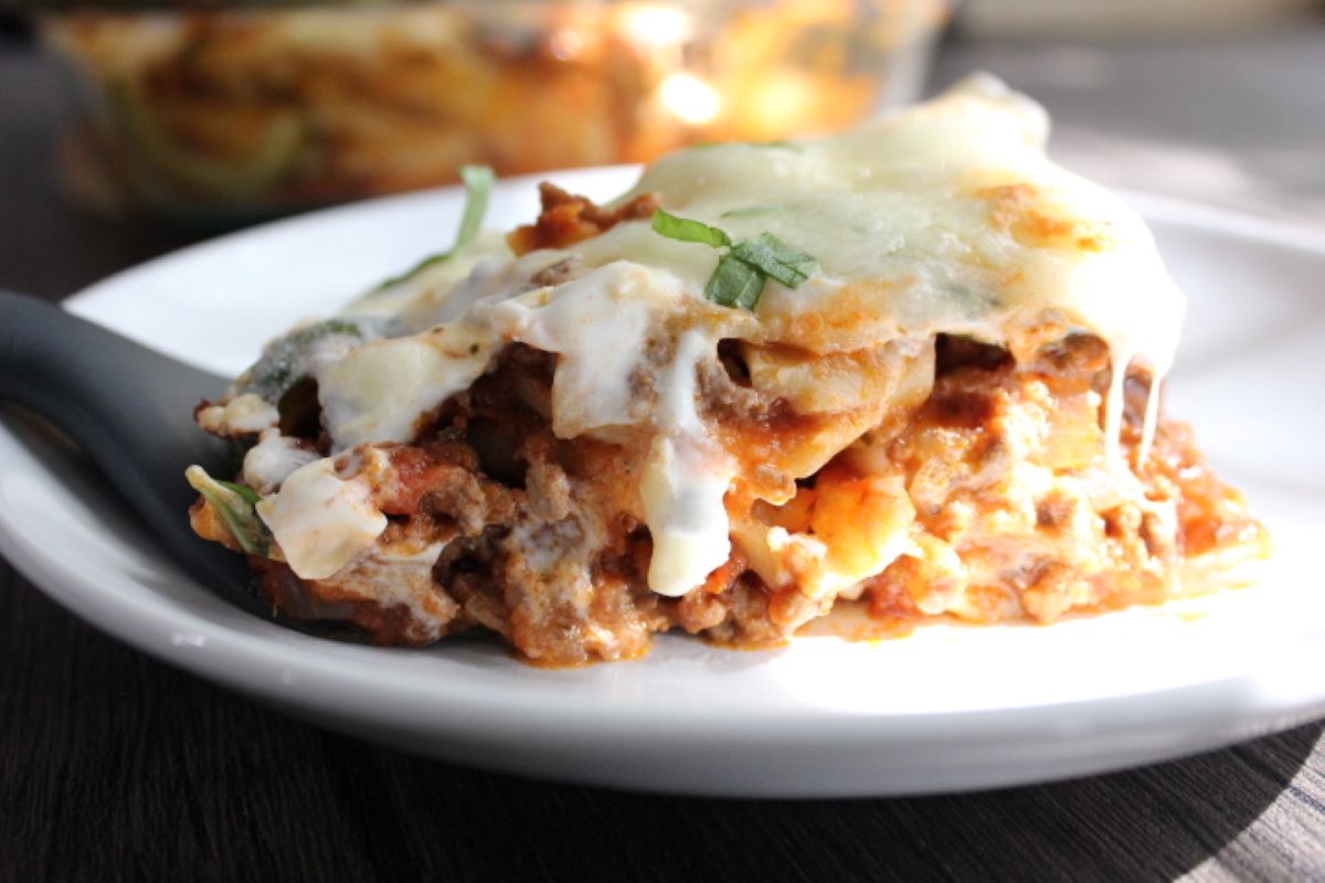 Image of lasagna casserole portioned out on a plate with a spatula.