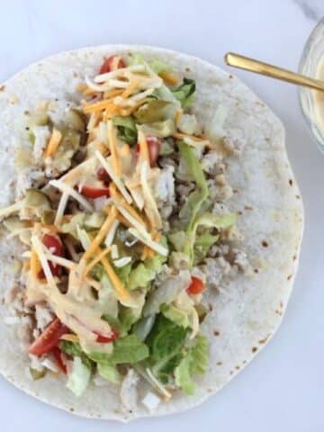 Image of Big Mac Wrap sitting opened face on counter with Big Mac sauce in a bowl on the side.